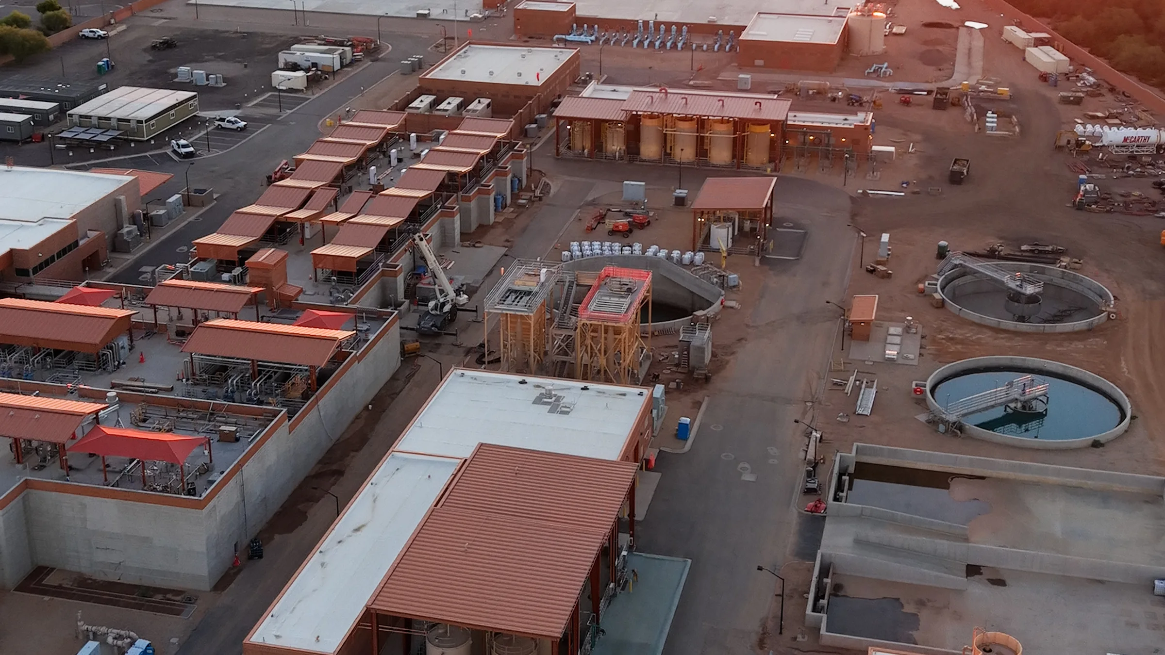 Closer aerial view of red-roofed equipment structures, circular basins and construction work at Signal Butte Water Treatment Plant in Mesa.