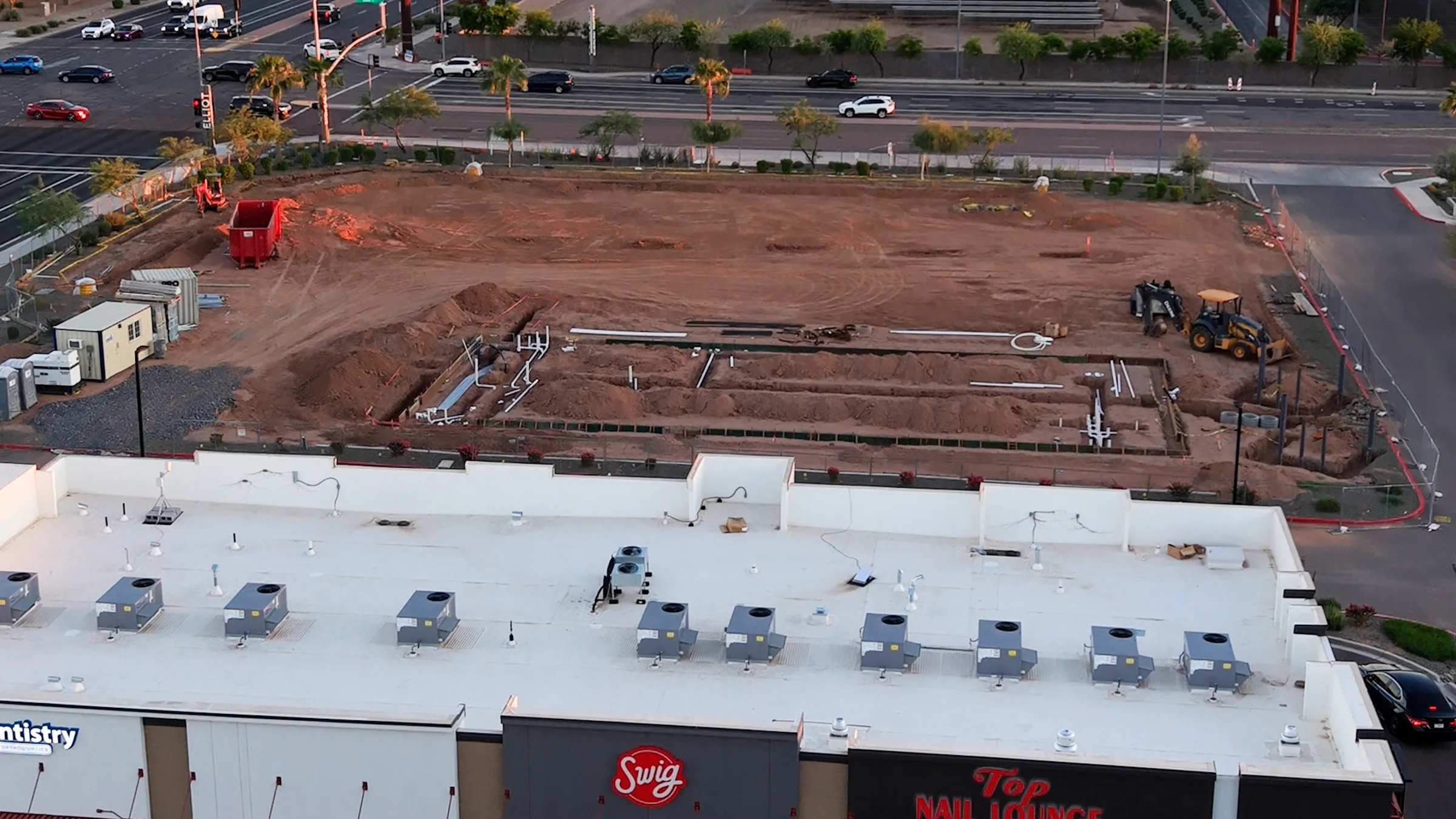 Trenches, white pipes and a rectangular construction footprint at the planned Circle K, with the neighboring retail strip in the foreground.
