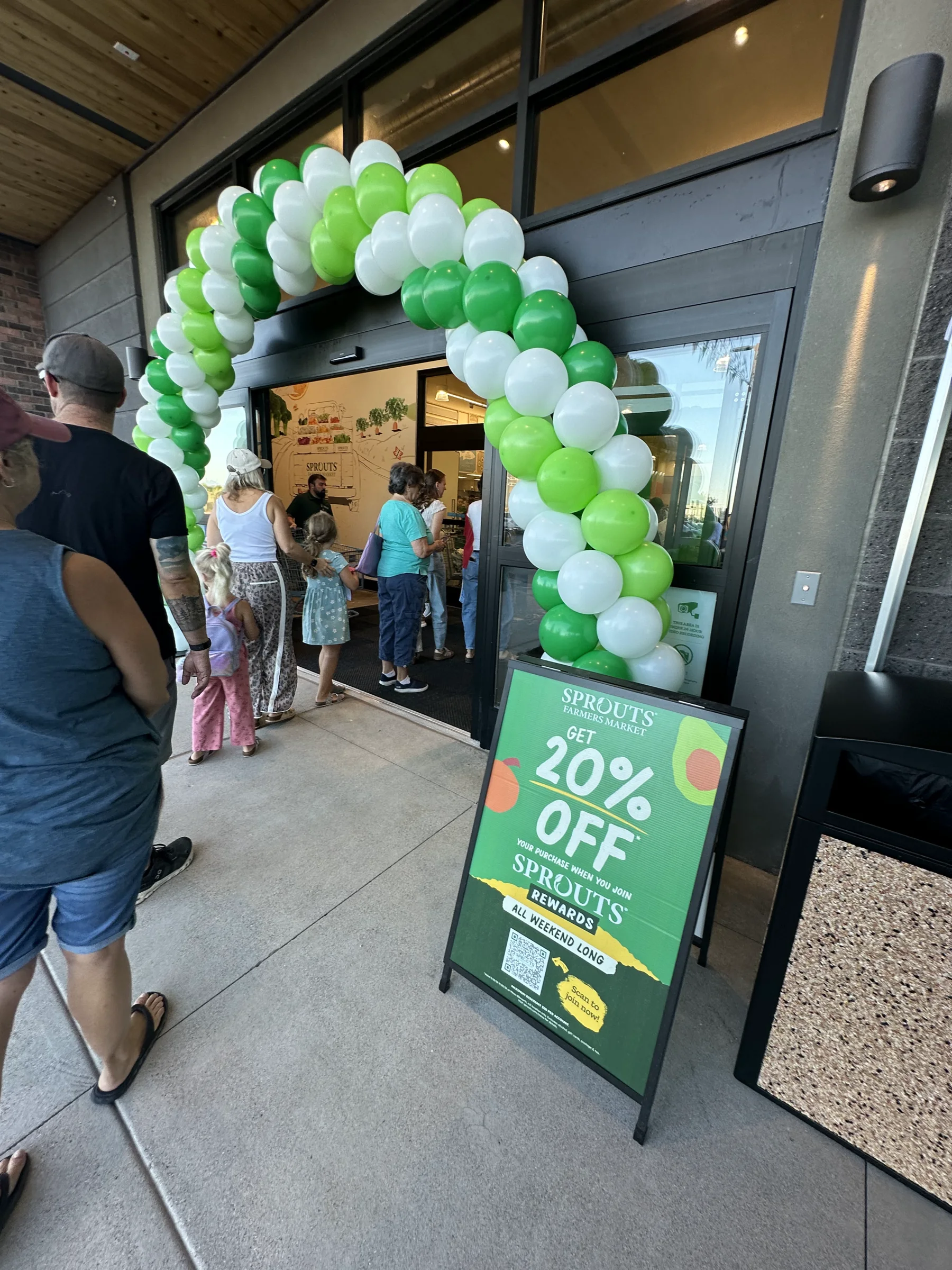 Shoppers enter the new Sprouts at Ellsworth and Ray in Mesa beneath a green-and-white balloon arch on opening day.