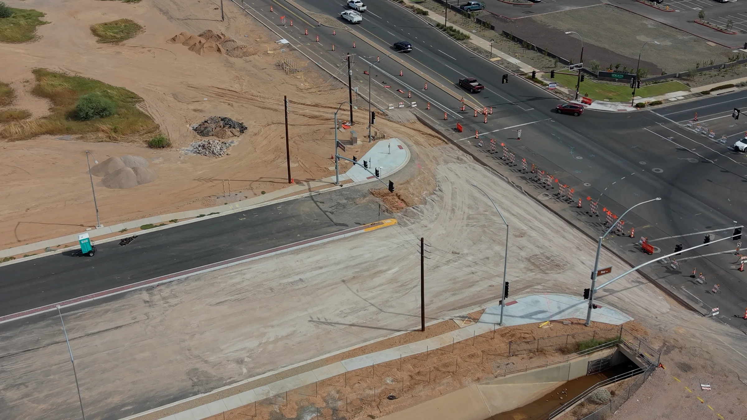 Close aerial view of unfinished roadway, concrete corner ramps, signal mast arms and utility poles at Ray and Ellsworth on September 21, 2026.