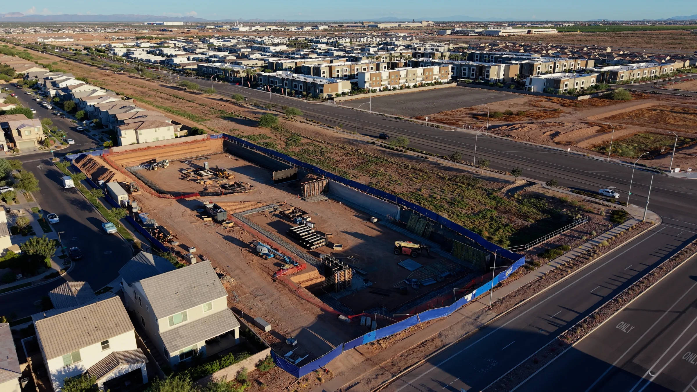 Aerial overview of the Guardian Storage at Cadence excavation, with concrete wall sections, construction equipment and neighboring homes.