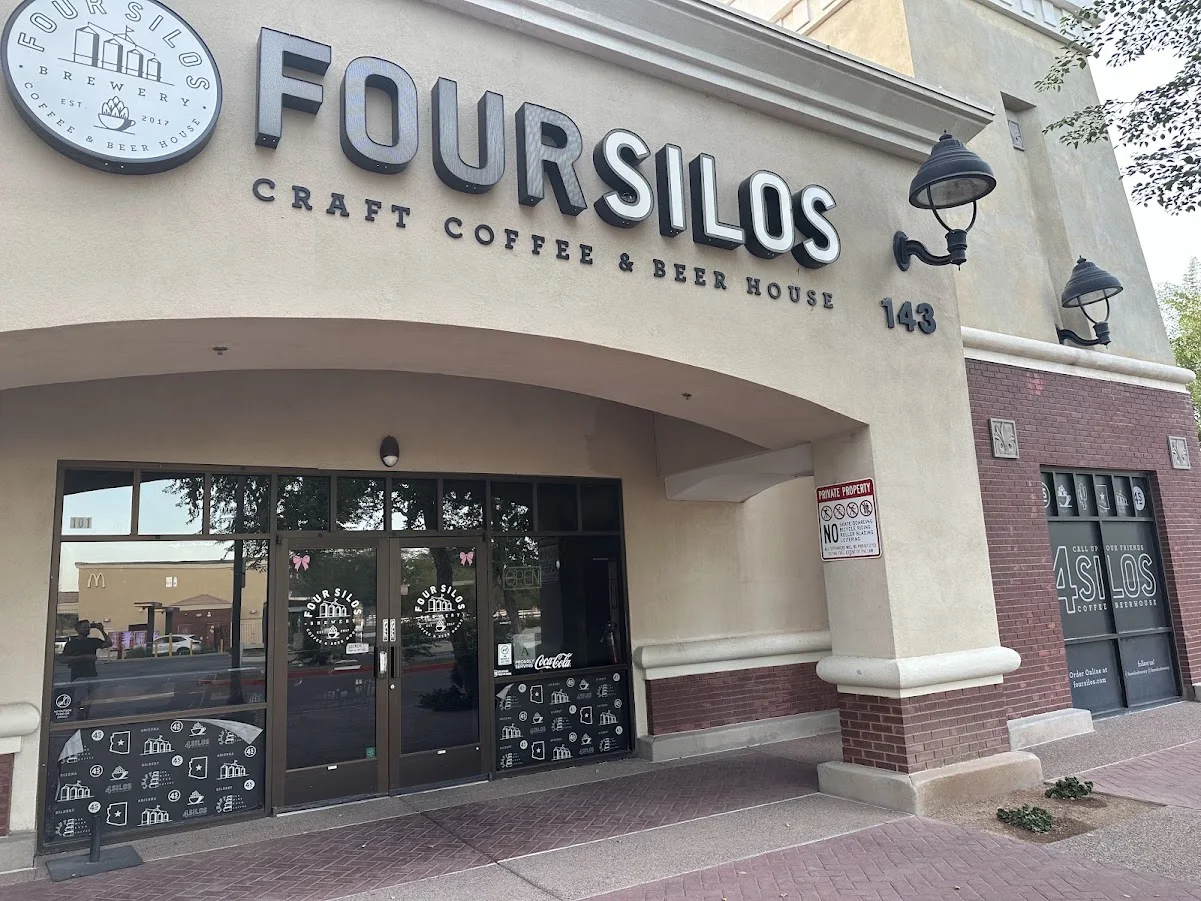 Four Silos Craft Coffee & Beer House storefront with large lettering, the number 143, black wall lamps and glass doors beneath a stucco arch.