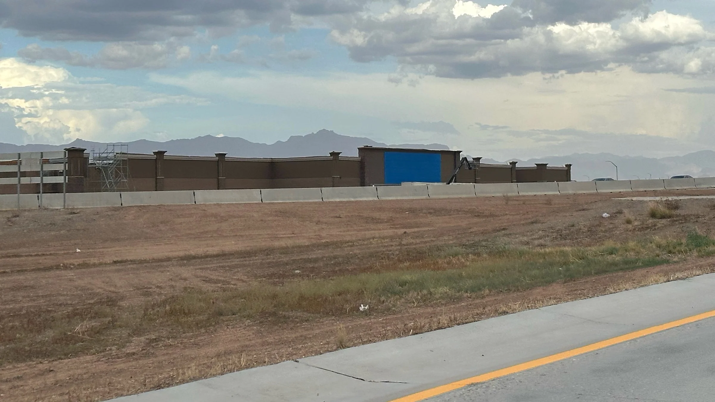 Walmart construction site near Signal Butte Road with the Superstition Mountains beneath storm clouds in the distance.
