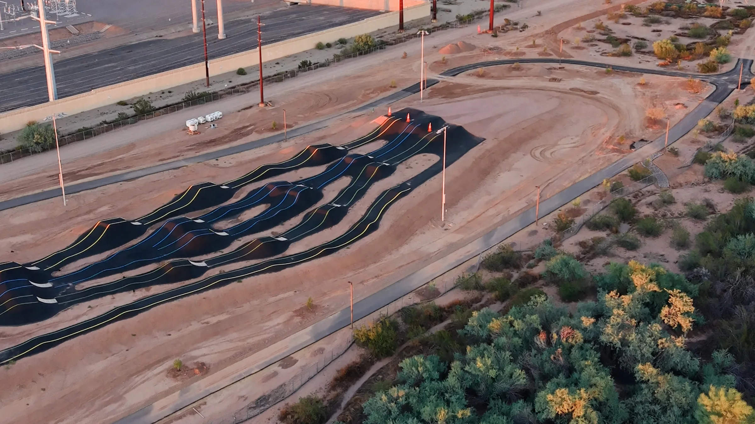 Aerial view of paved rollers and banked turns with blue, yellow and green markings at Signal Butte Park’s bike area in Mesa.