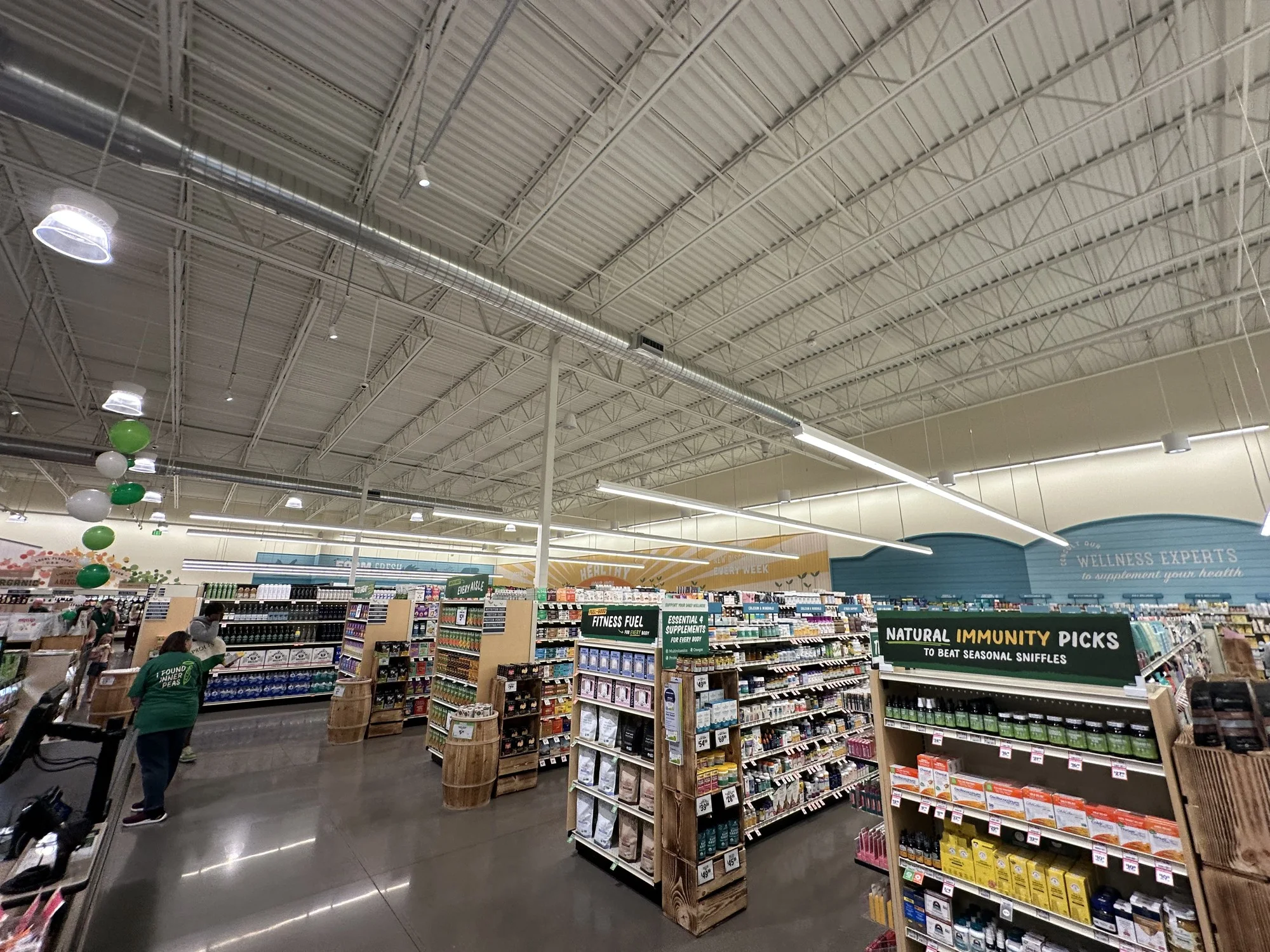 Stocked grocery and wellness aisles beneath a high white ceiling inside the new Mesa-Ellsworth Sprouts on opening day.