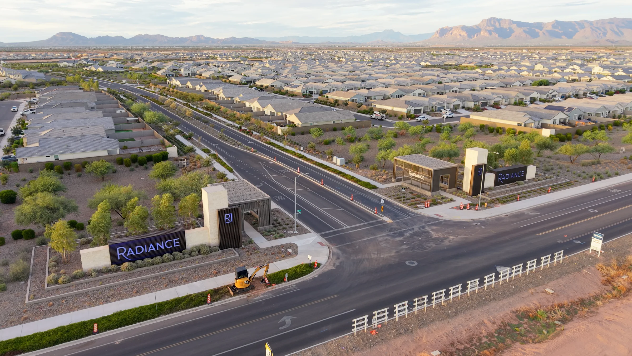 Radiance entrance monuments beside landscaped streets, with homes and the Superstition Mountains in the distance.