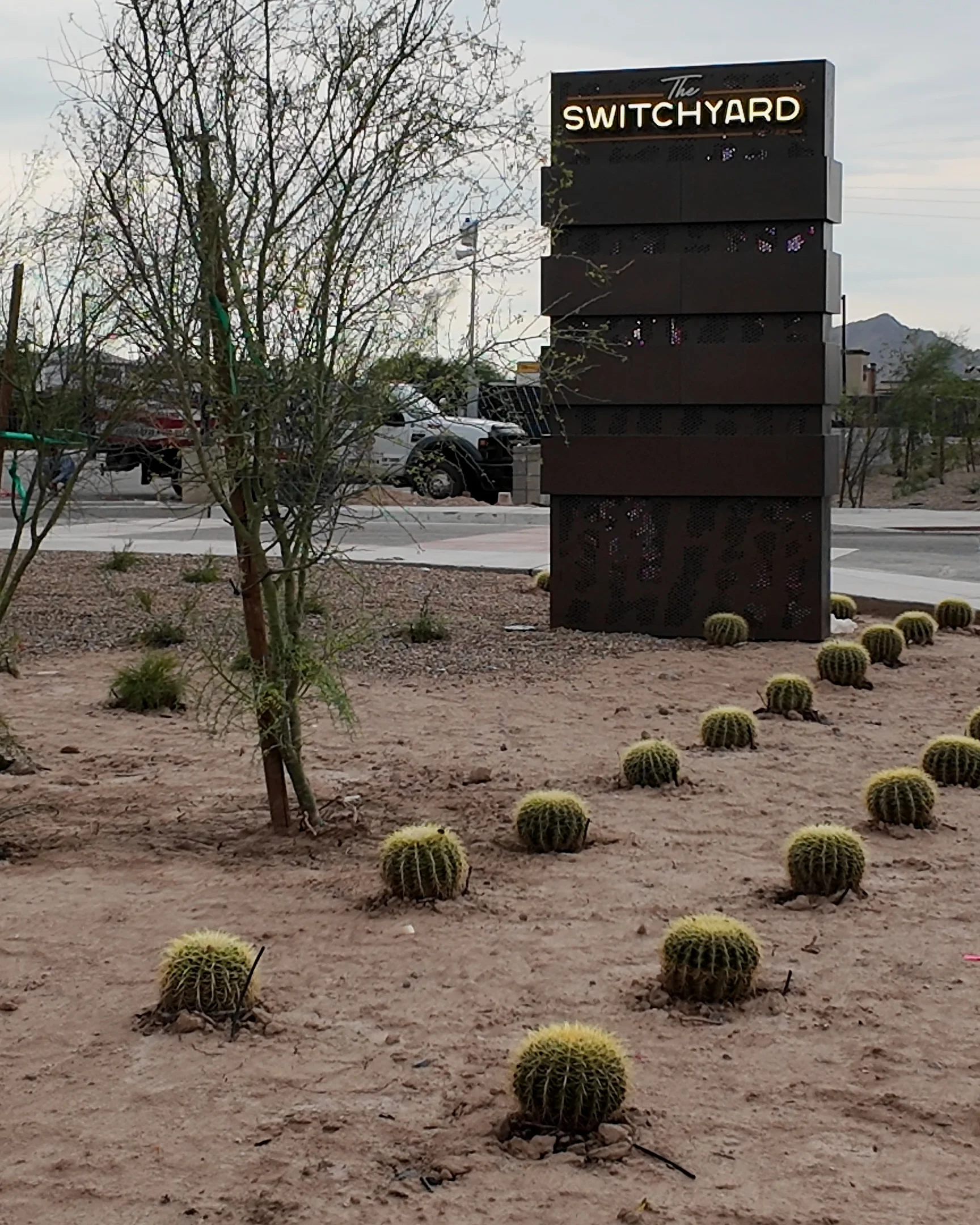 Rows of barrel cactus lead toward The Switchyard’s tall monument sign.