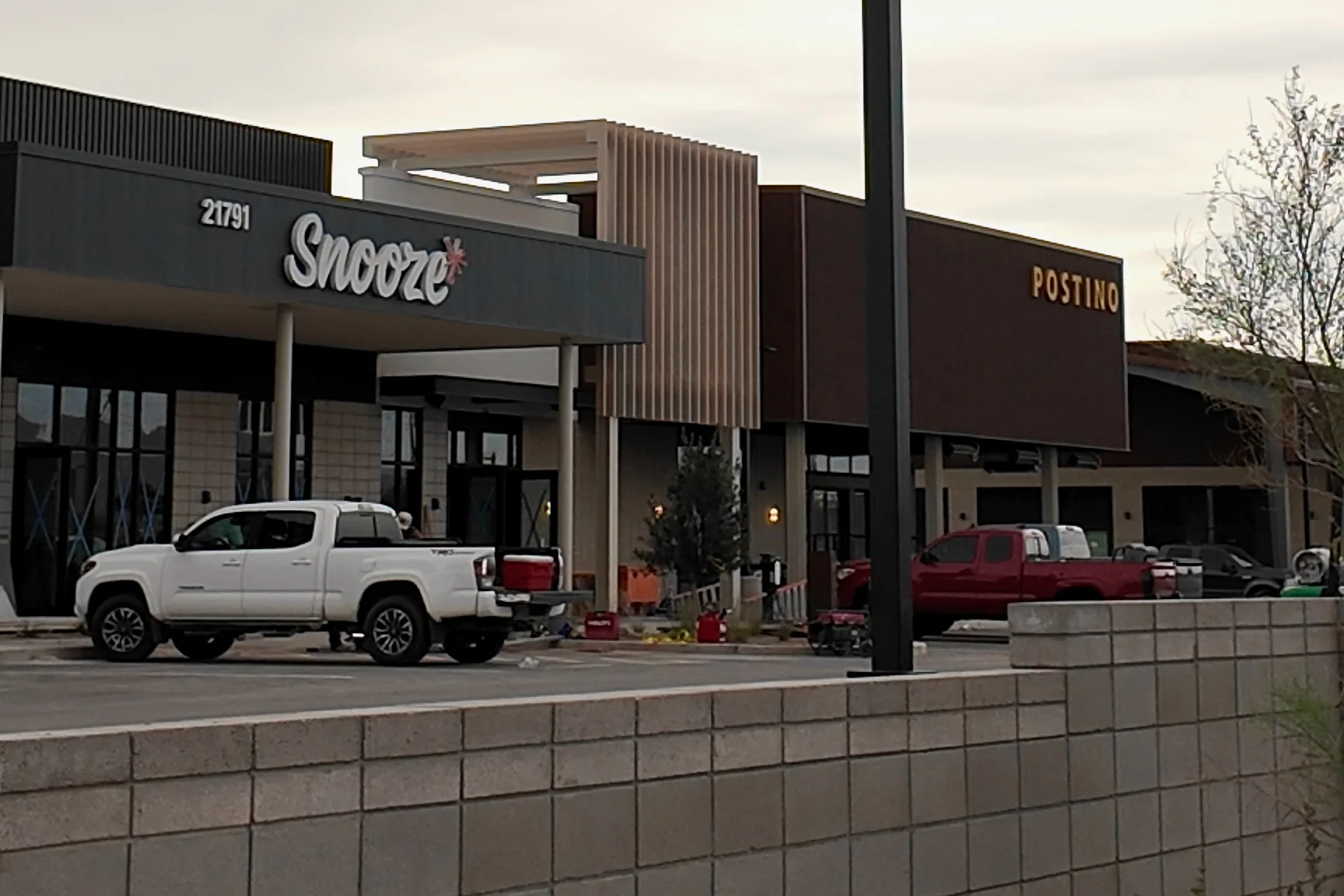 Snooze and Postino signs above storefronts, with work trucks and construction materials outside.